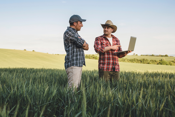 dos agricultores en un cultivo con un ordenador portátil