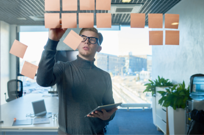 un joven frente una cristal con postits pegados