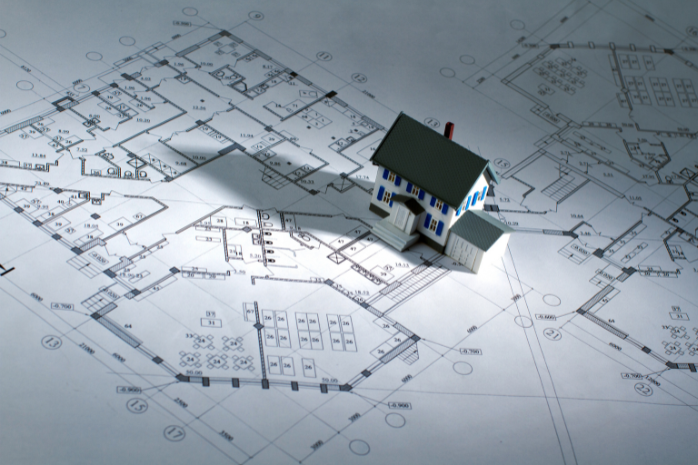 una casa de juguete sobre unos planos de construcción