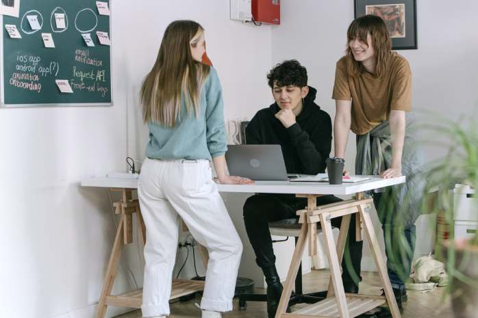 tres jóvenes en torno a una mesa de trabajo