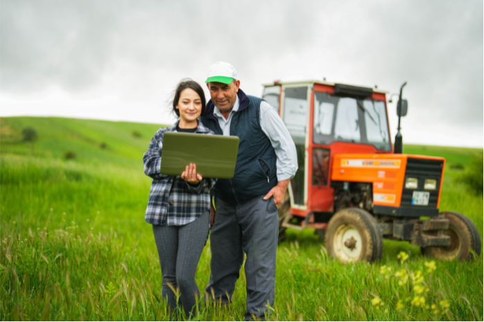 dos personas en un campo de cultivo frente a un tractor