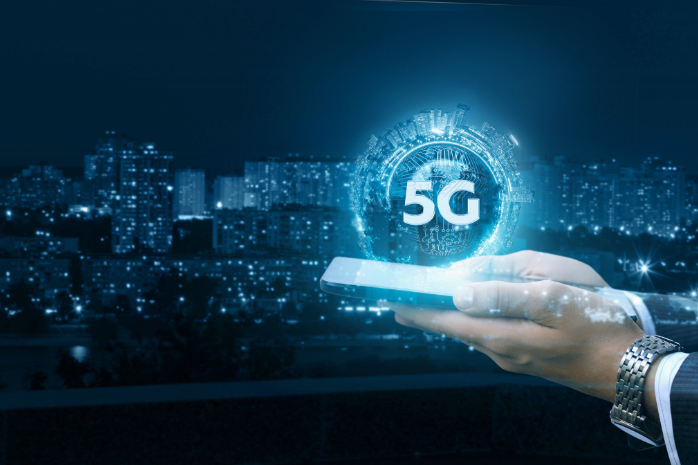 unas manos sosteniendo un teléfono móvil con las siglas 5G emergiendo de él