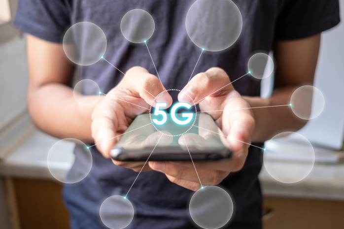 un joven usando un móvil del que salen las siglas 5G