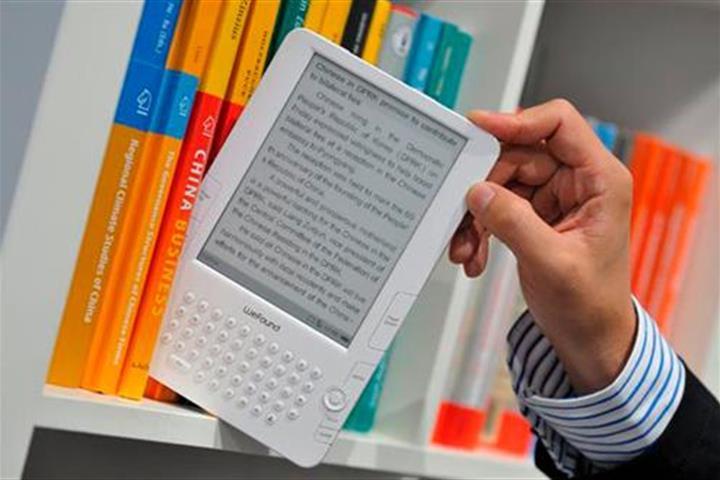 Una persona saca un libro electrónico de una estantería con libros