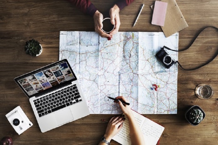 Dos personas organizando una ruta con un mapa y un ordenador portátil en una mesa